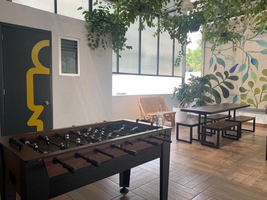 Zona de juegos con futbolito y mural de hojas