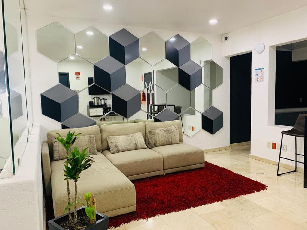 Lobby de CCM Oficinas con muro de espejos hexagonales y sala de espera
