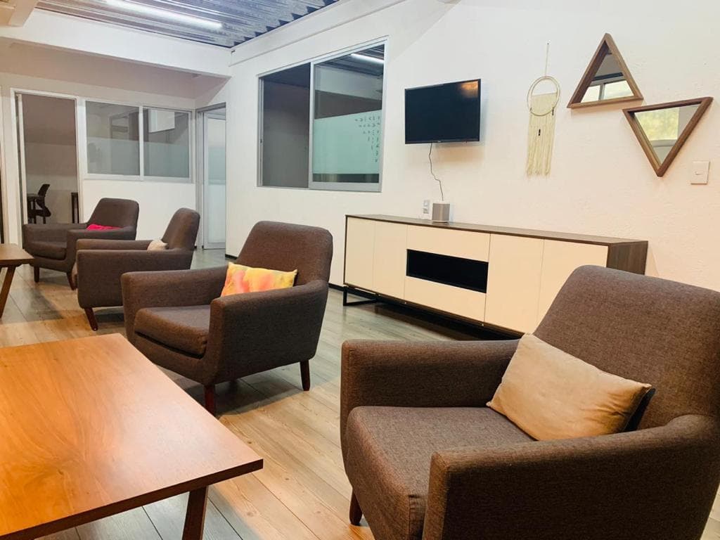 Sala de estar con sillones cafés, pantalla y credenza