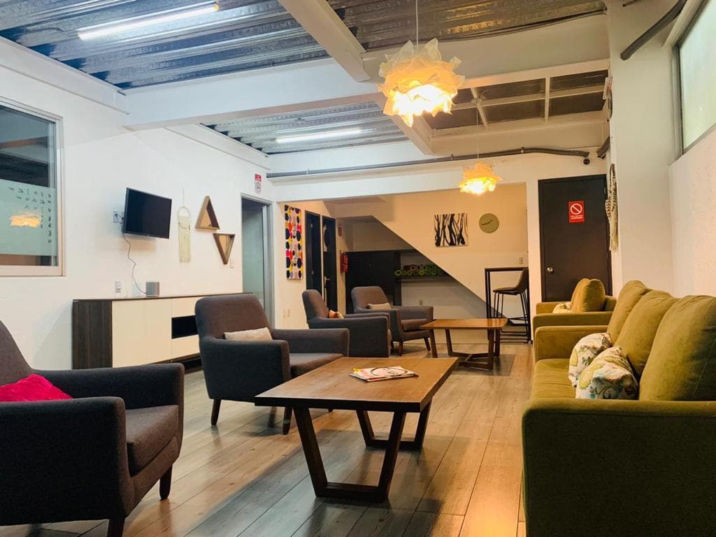 Área común con sillones, mesas de centro y pantalla