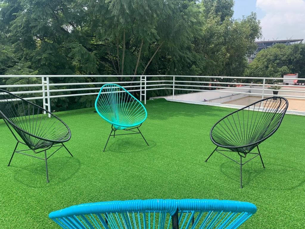 Zona de descanso en la terraza con sillas Acapulco y vista a los árboles